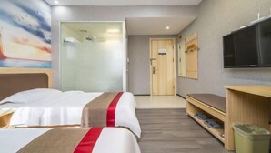 Habitación de hotel con dos camas, televisión, un banco y una puerta que da a un baño.