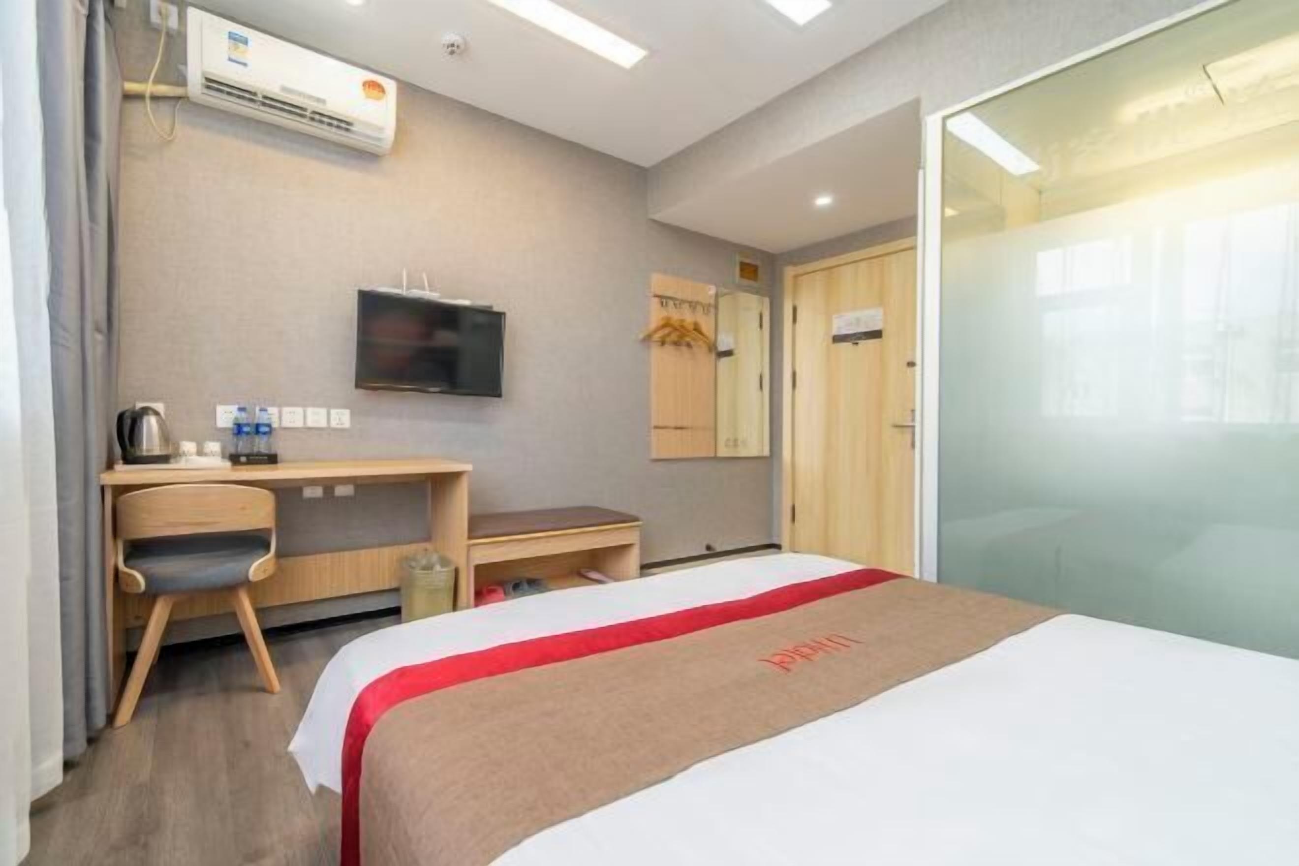Une chambre d’hôtel comprenant un lit, un bureau, une chaise, une télévision et une armoire.