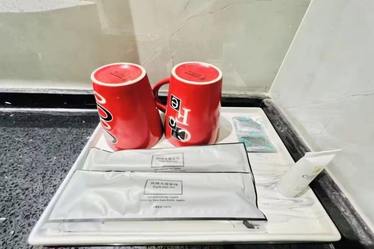 A tray with two red mugs and a white plate with a card.