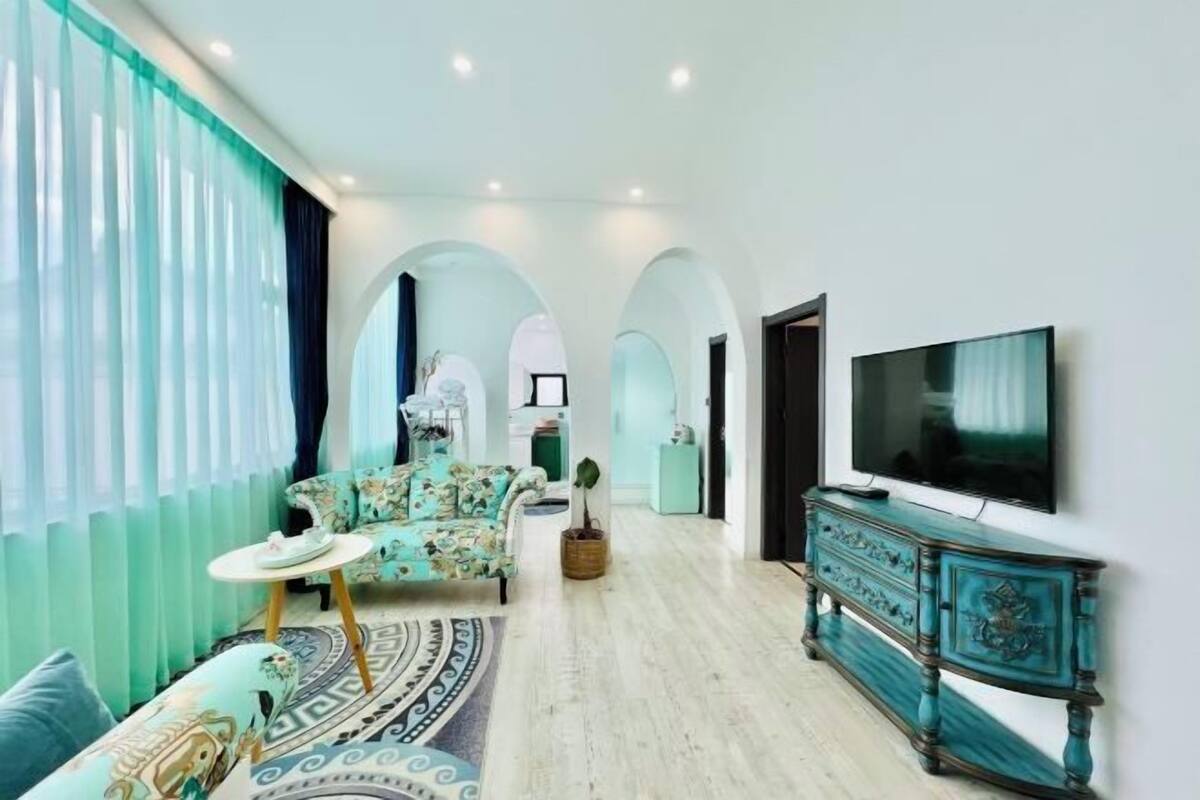 A modern living room with a sofa, a television, and a patterned rug.