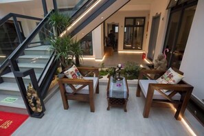 A hotel lobby with a staircase, seating area with chairs and a small table, and a plant. - Hotel Du Temps Perdu (Dali City)