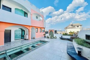 Ein modernes Gebäude mit Pool, Bogenöffnungen und blauem Himmel.