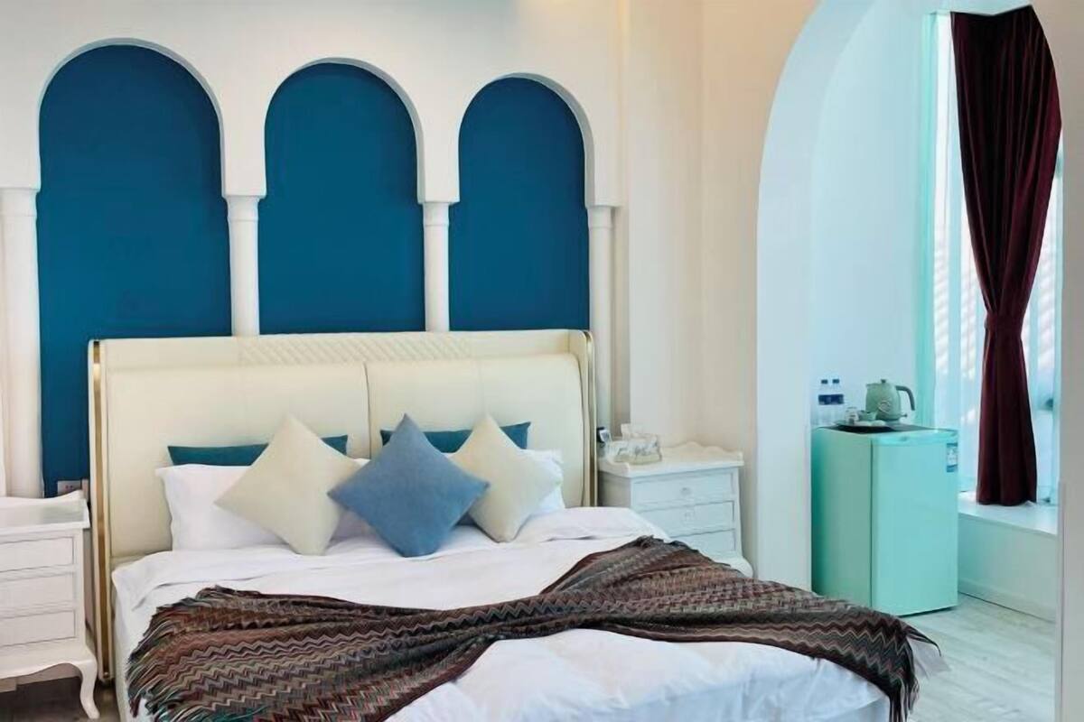 A bed with a white headboard, a patterned throw blanket, and multiple pillows.