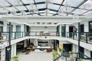 Ein geräumiger, mehrstöckiger Innenraum mit einer zentralen offenen Zone, Glasgeländern und hängenden Leuchten.