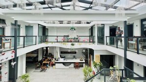 A spacious, multi-level interior with a central open area, glass railings, and modern furnishings. - Hotel Du Temps Perdu (Dali City)