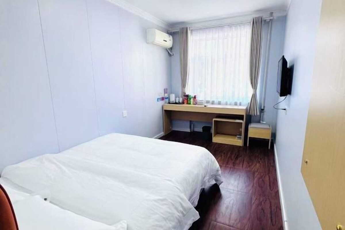 A hotel room with a bed, a desk, a chair, and a television.