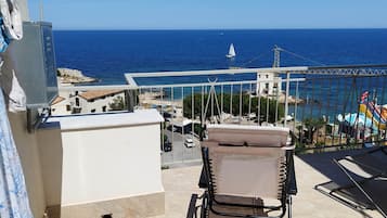 Un balcon avec vue sur la mer, un voilier et une aire de jeux colorée.