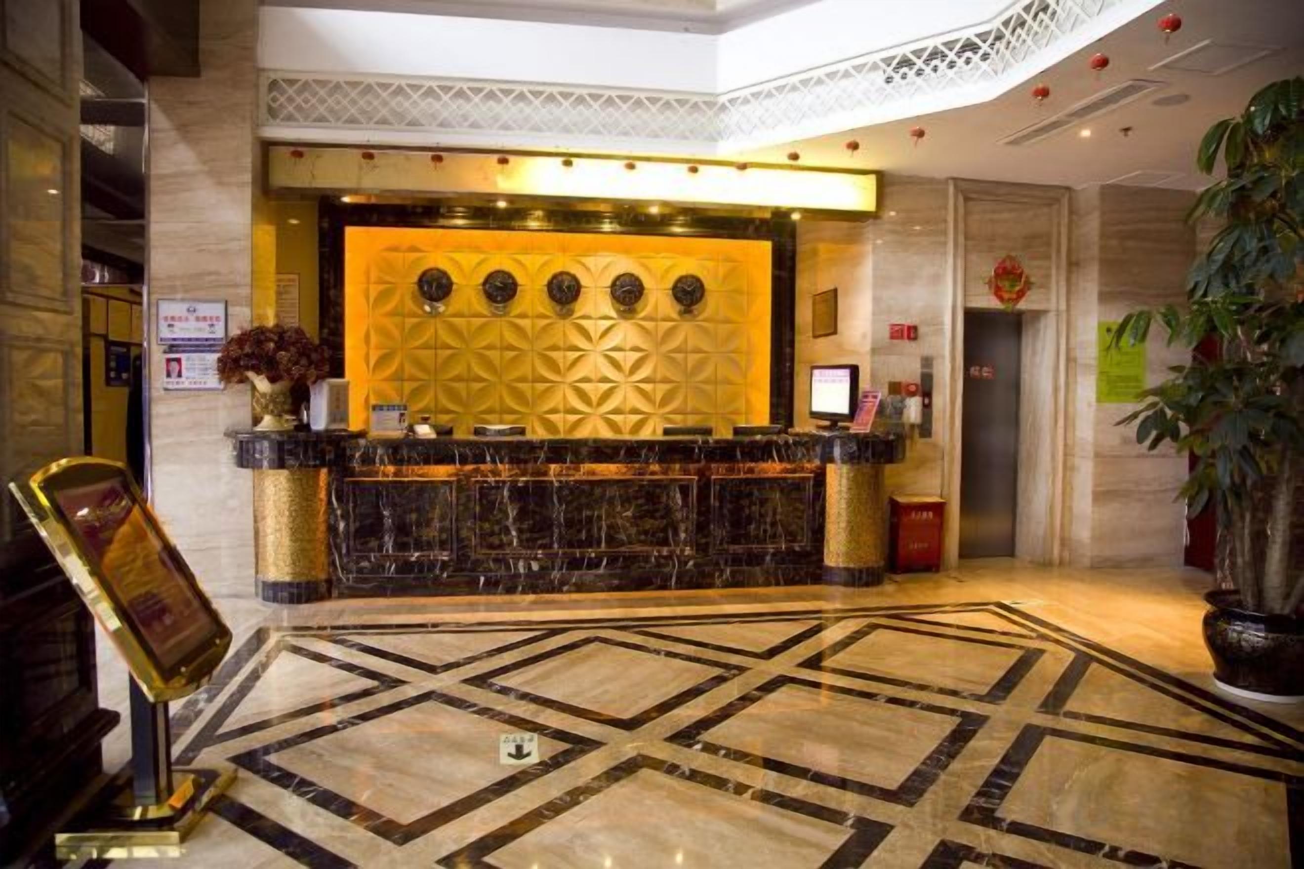 A hotel reception area with a marble floor, a reception desk, and a decorative wall.