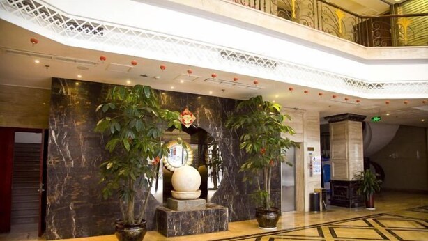A lobby with marble walls, a decorative wall piece, and potted plants. - Meike Hotel (Wenzhou)