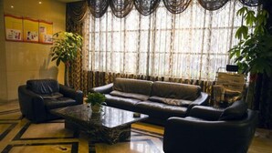 A modern living room with a sofa, two armchairs, a coffee table, and a large plant. - Meike Hotel (Wenzhou)