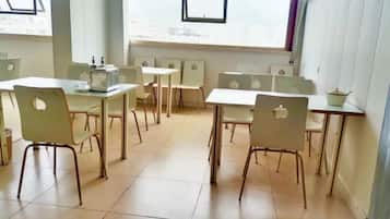 A room with multiple tables and chairs, large windows, and a view of the city.