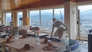 A dining area with a high ceiling and large windows overlooking a cityscape. - Di Carbone Hotel Gastrobar (Facatativá)