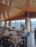 A dining area with a high ceiling and large windows overlooking a cityscape.