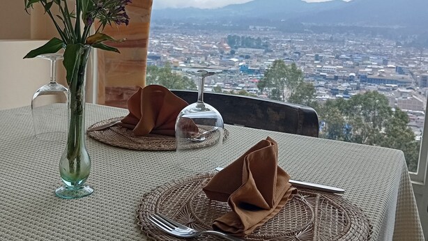 A table set with a clear glass vase, a clear glass dome, and a woven placemat. - Di Carbone Hotel Gastrobar (Facatativá)