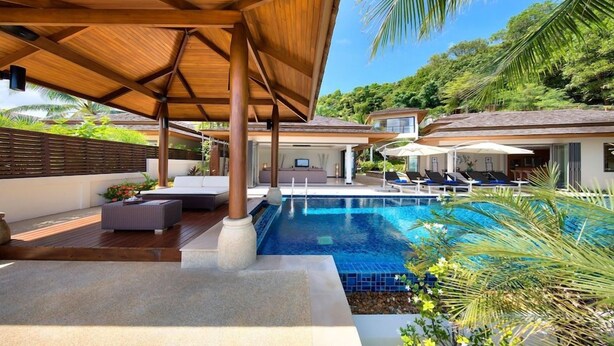 A swimming pool with lounge chairs, a covered seating area, and a view of a house. - Baan Leelawadee (Koh Samui)