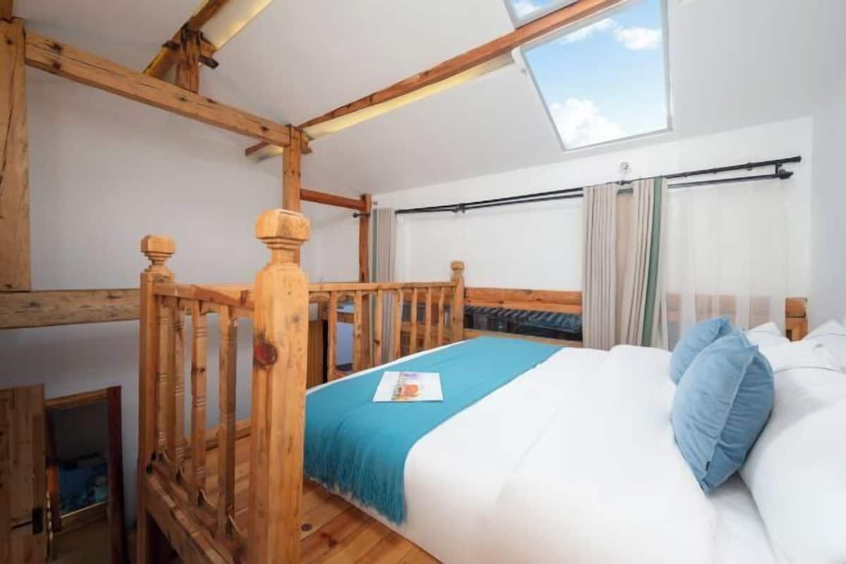 Un dormitorio con estructura de cama de madera, tragaluz y vistas al exterior.