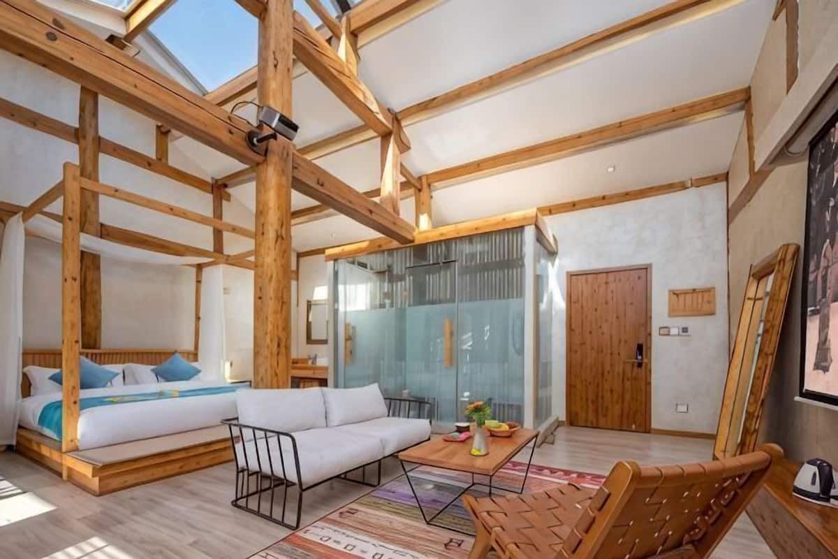A room with a high ceiling, wooden beams, a sofa, a small table, and a glass partition.