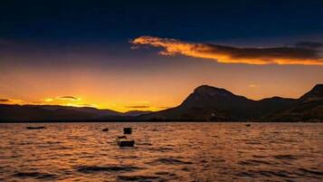 Un atardecer sobre un cuerpo de agua con montañas al fondo.
