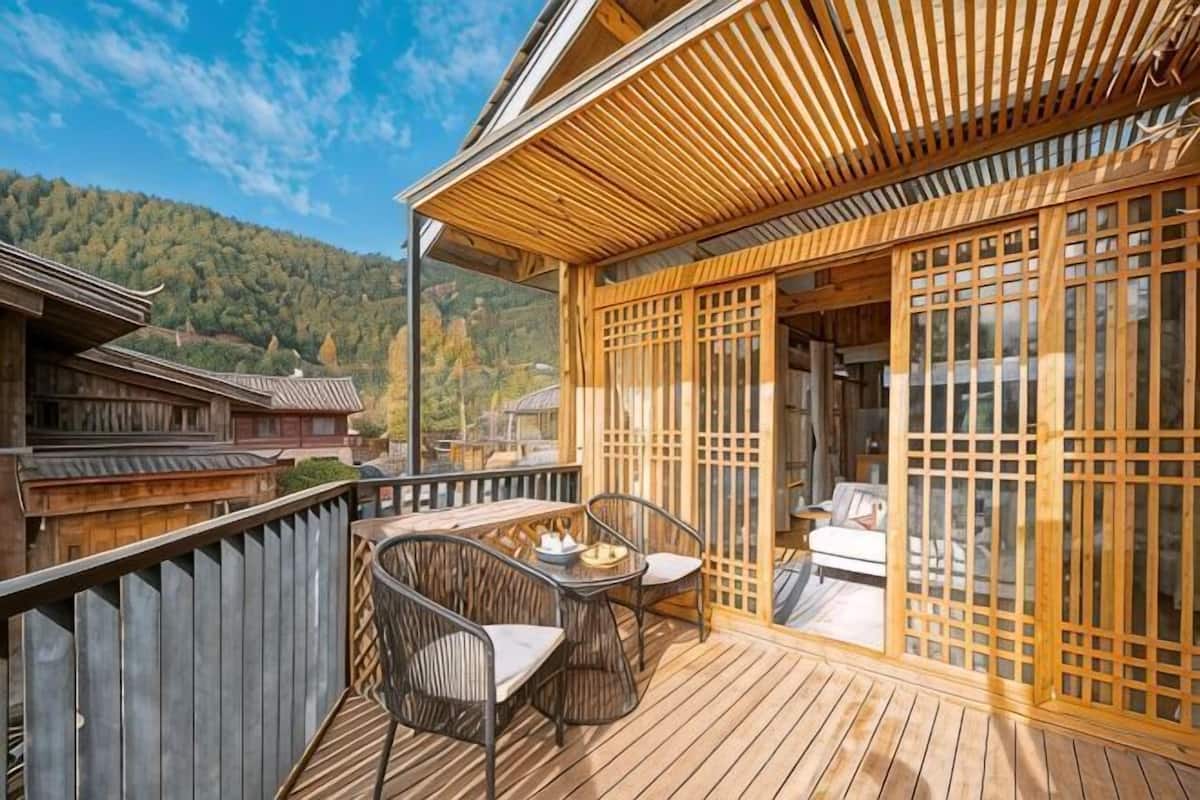 Una terraza de madera con una habitación al estilo tradicional japonés, que incluye esteras de tatami y puertas correderas.