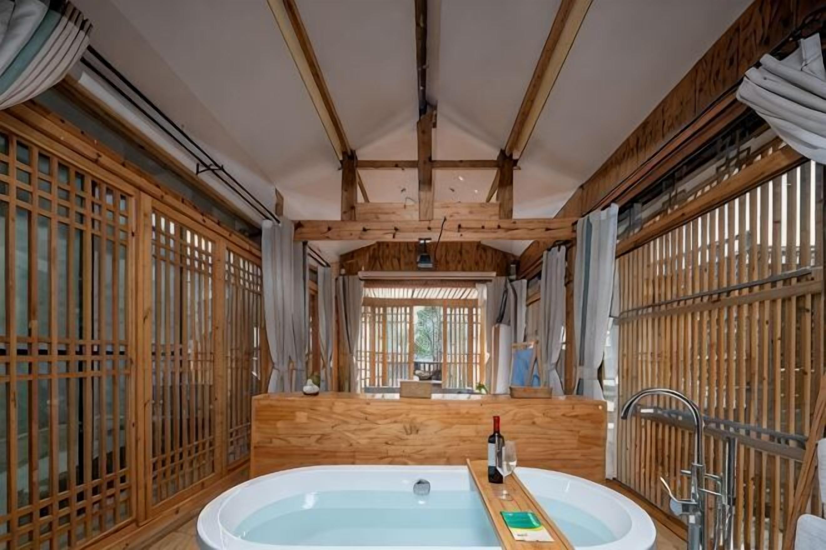 A traditional Japanese-style room with a wooden interior, a large bathtub, and sliding doors.