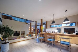A modern kitchen with a bar area, wooden furniture, and pendant lighting.