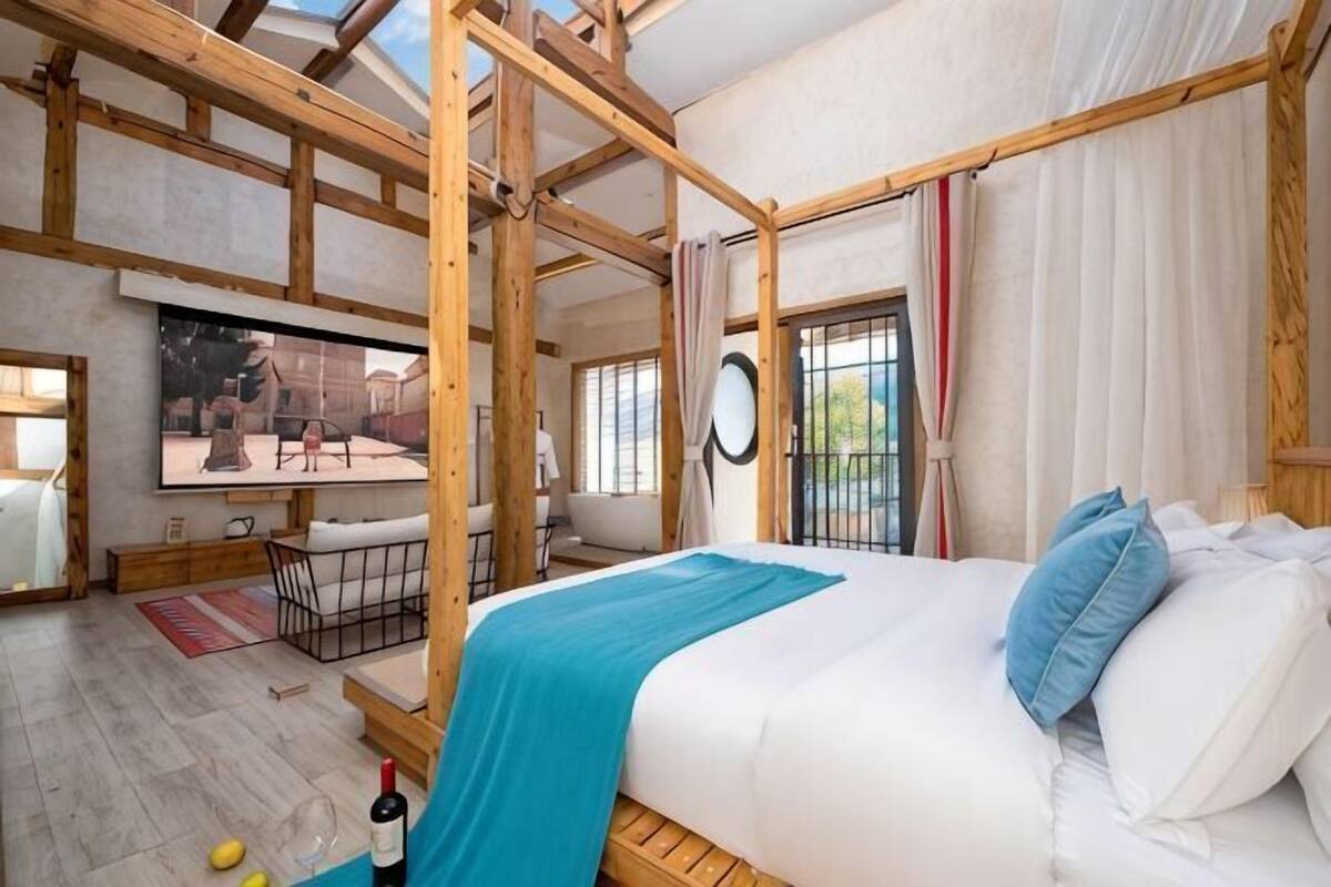 Una habitación con cama, televisión, mesa de comedor y ventana.
