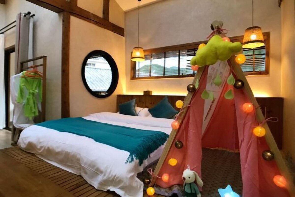A cozy bedroom with a bed, a tent-like structure with lights, a mirror, and a window.
