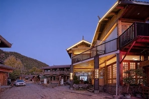 A traditional wooden building with a balcony and a covered outdoor seating area. - Lugu Huzi yueshanshe Inn (Ninglang)