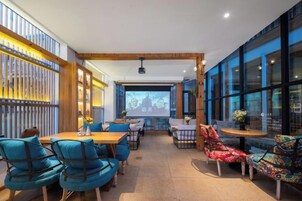 Un restaurante con interior de madera, mesas, sillas y una pantalla de proyección.