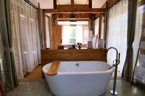 A bathroom with a freestanding bathtub, wooden paneling, and a window with curtains. - Lugu Huzi yueshanshe Inn (Ninglang)