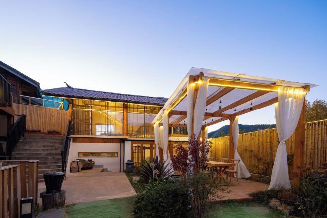 Een modern huis met een overdekt terras, een trap en een omheind gazon.