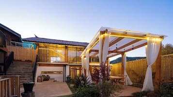 Een modern huis met een overdekt terras, een trap en een omheind gazon.
