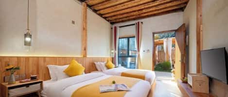 Un dormitorio con dos camas, vigas de madera en el techo, un televisor y una ventana con cortinas.