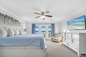 Relax in this serene bedroom with a large bed, flat-screen TV, and ocean views from the balcony.