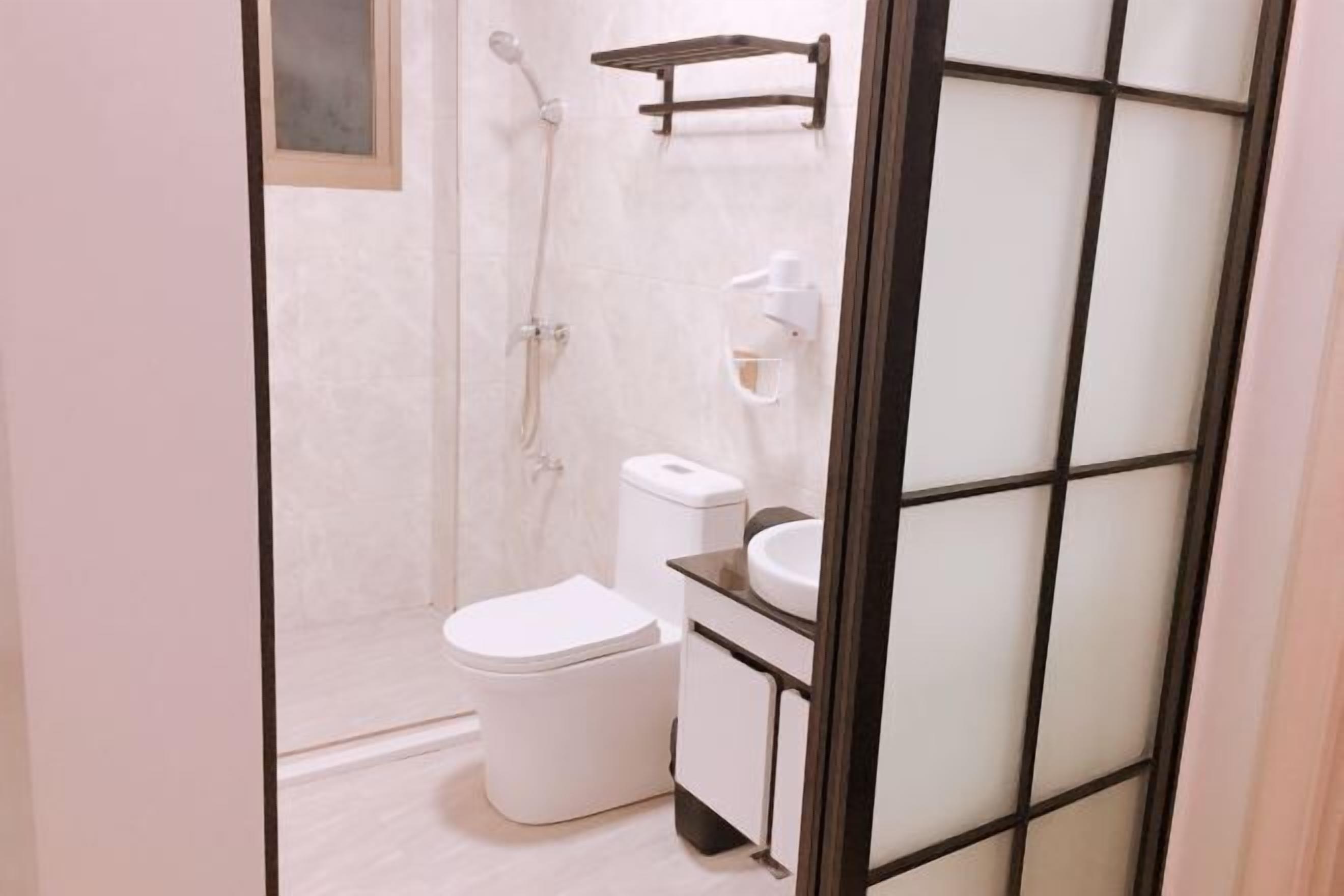 A bathroom with a toilet, a sink, a shower, and a towel rack.
