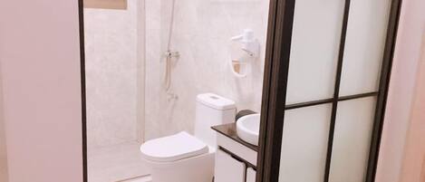 A bathroom with a toilet, a sink, a shower, and a towel rack.