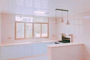 A kitchen with a window, a sink, cabinets, and hanging pendant lights.