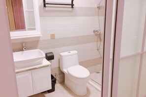 A bathroom with a white sink, toilet, and shower.
