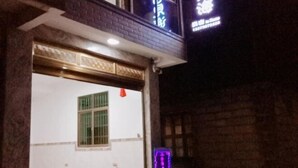 Ein Gebäudeeingang mit einem Schild über der Tür, einem Fenster mit grünen Streben und einem violetten Laternenpfahl.