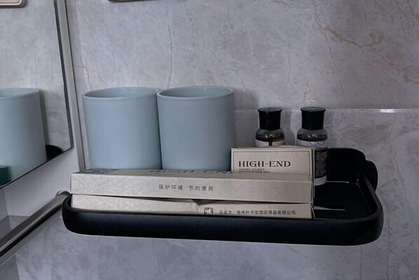 A bathroom vanity with a mirror, two light blue cylindrical containers, a black tray, and a box labeled 'HIGH-END'.
