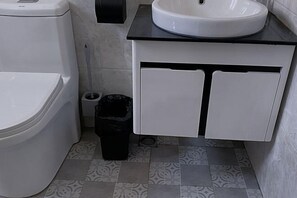 A bathroom with a toilet, sink, and cabinet.