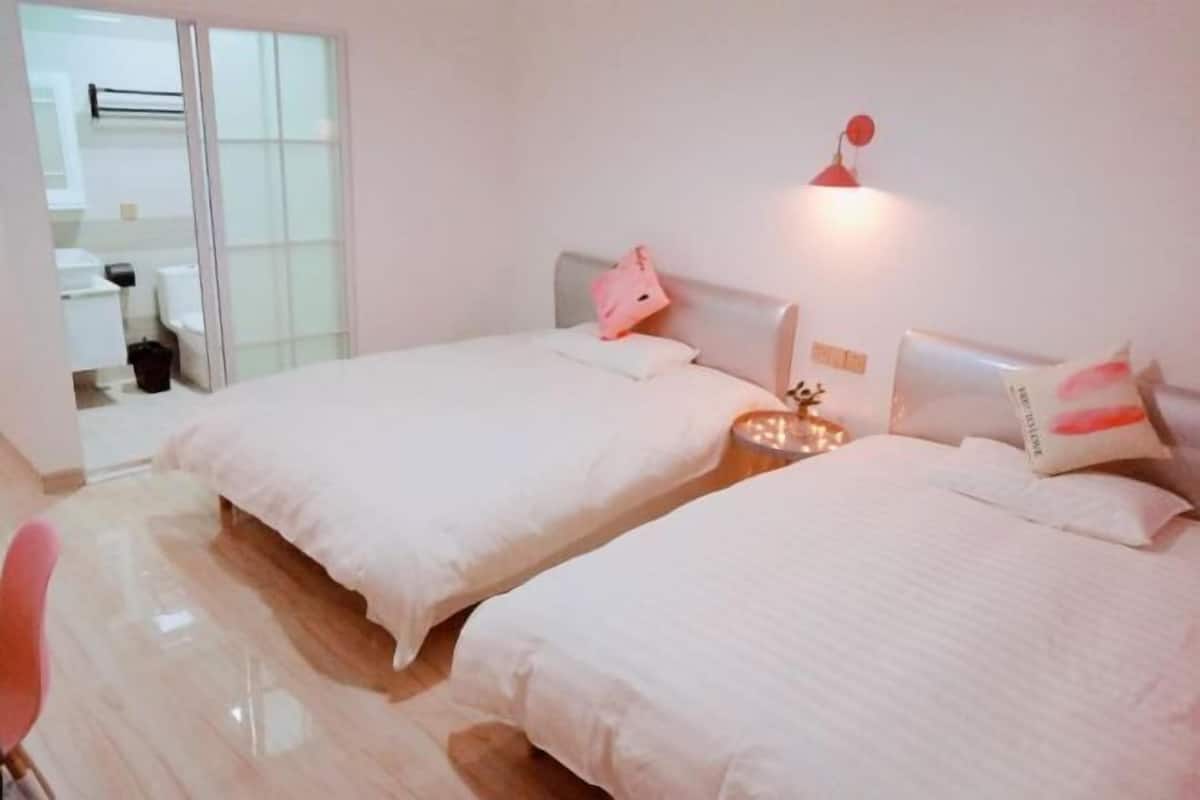 Habitación de hotel con dos camas, una mesita pequeña y una silla.