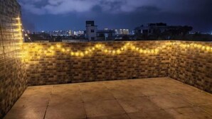 Eine Dachterrasse mit Backsteinmauer und Lichterkette.