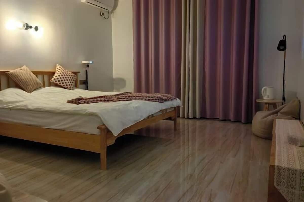 Un dormitorio con cama de madera, una mesita de noche con lámpara, y una ventana con cortinas.