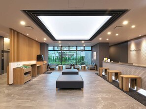 A modern hotel lobby with a reception desk, seating area, and a large skylight. - Hotel Route Inn Kato (Kato)