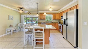 A kitchen with a central island, wooden cabinets, stainless steel appliances, and pendant lighting. - PARADISE RETREAT A 3/2 PET FRIENDLY POOL HOUSE (Bradenton)