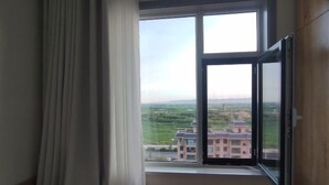 Una habitación con un ventanal que ofrece vistas a un edificio y follaje.