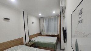 Habitación de hotel con dos camas, una ventana con cortinas translúcidas, un televisor montado en la pared y un cartel con el texto "ME and YOU forever".