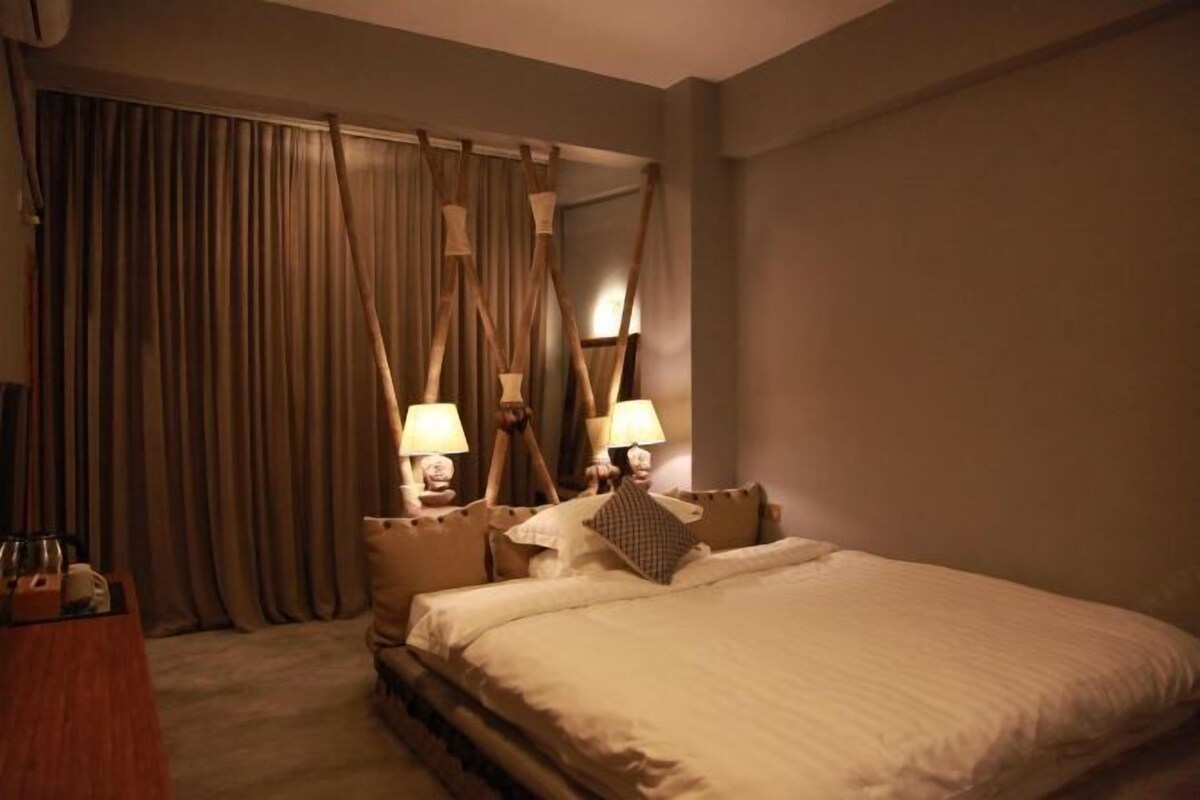 A hotel room with a large bed, a desk with a lamp, and curtains.