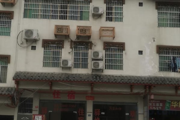 A building with multiple air conditioning units, a tiled roof, and a storefront with signage.